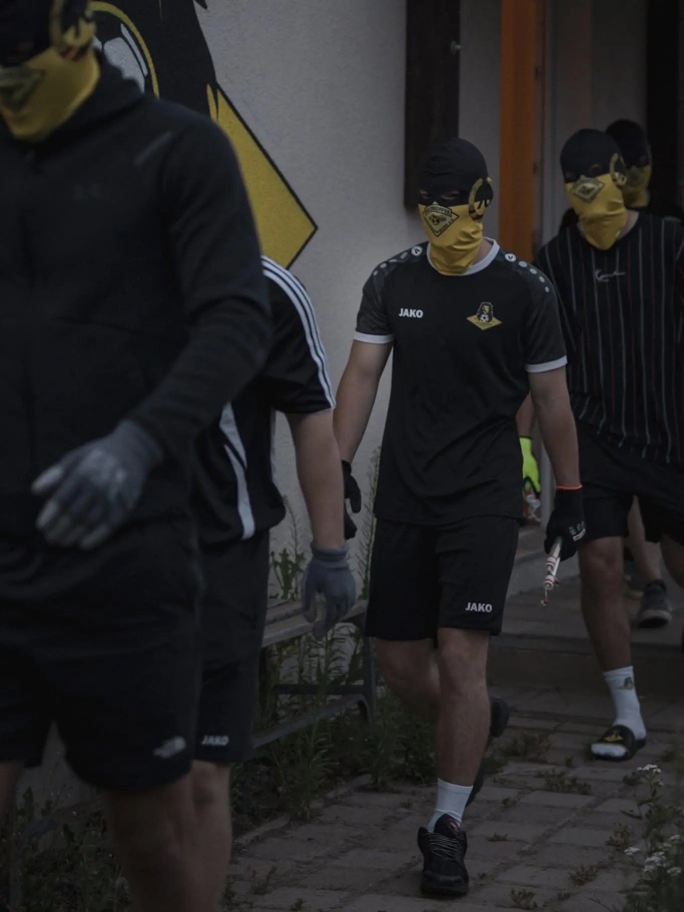 Spieler in Schwarz laufen an der Wand mit dem Vereinswappen vorbei.