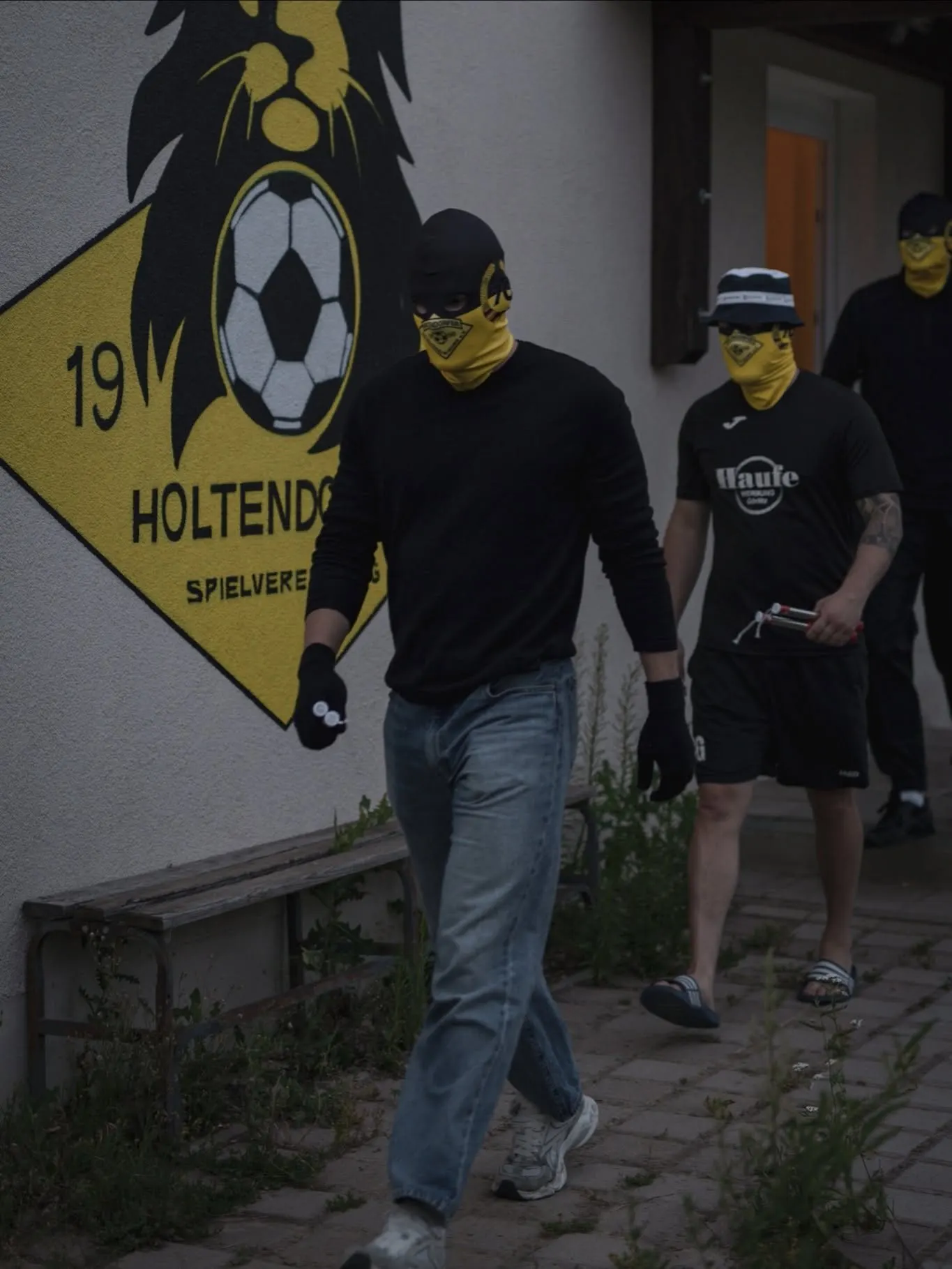Die Mannschaft kommt mit gelben Sturmhauben aus dem Vereinsheim.