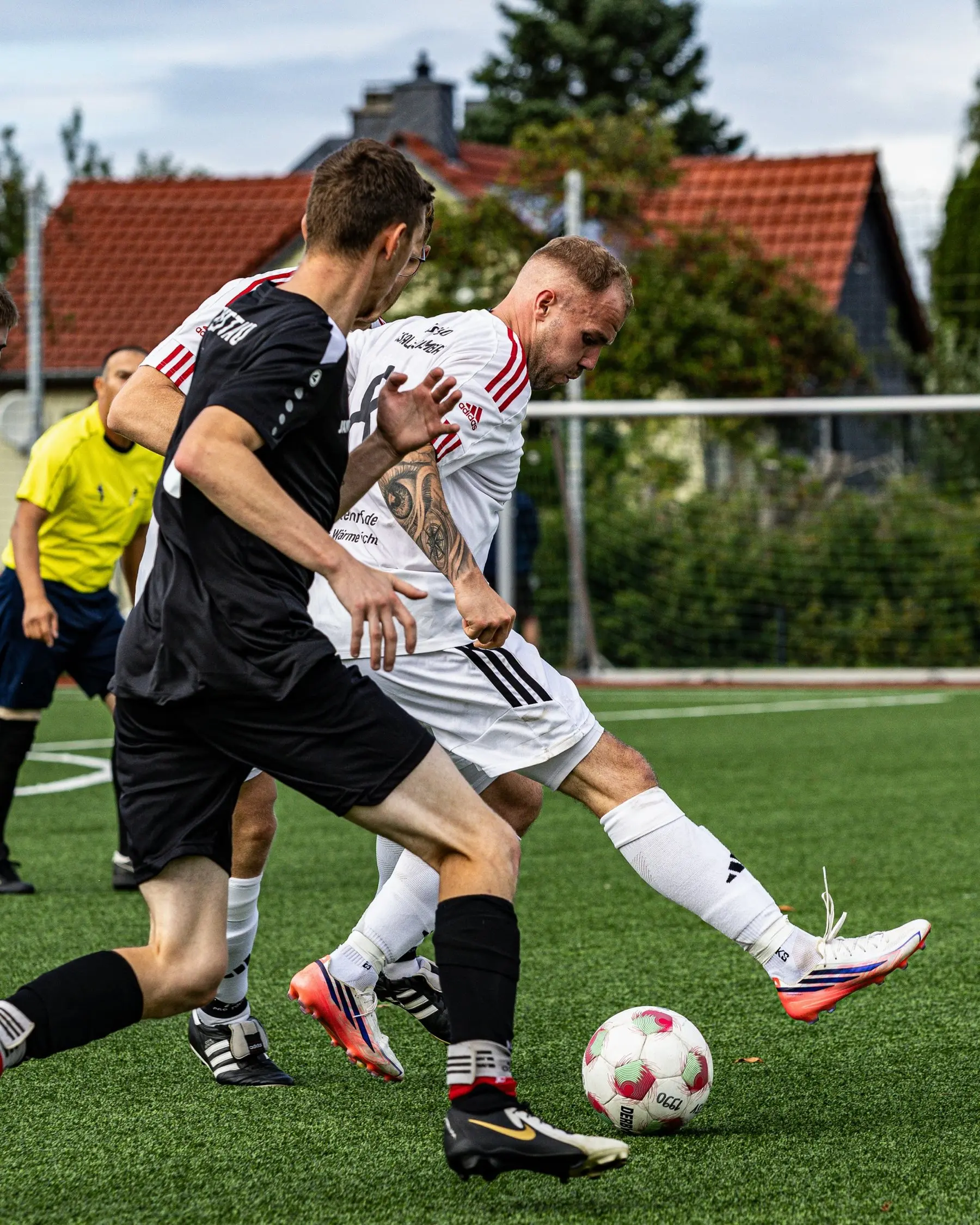 Spieler in Schwarz zieht mit dem Ball an einem Gegner vorbei.