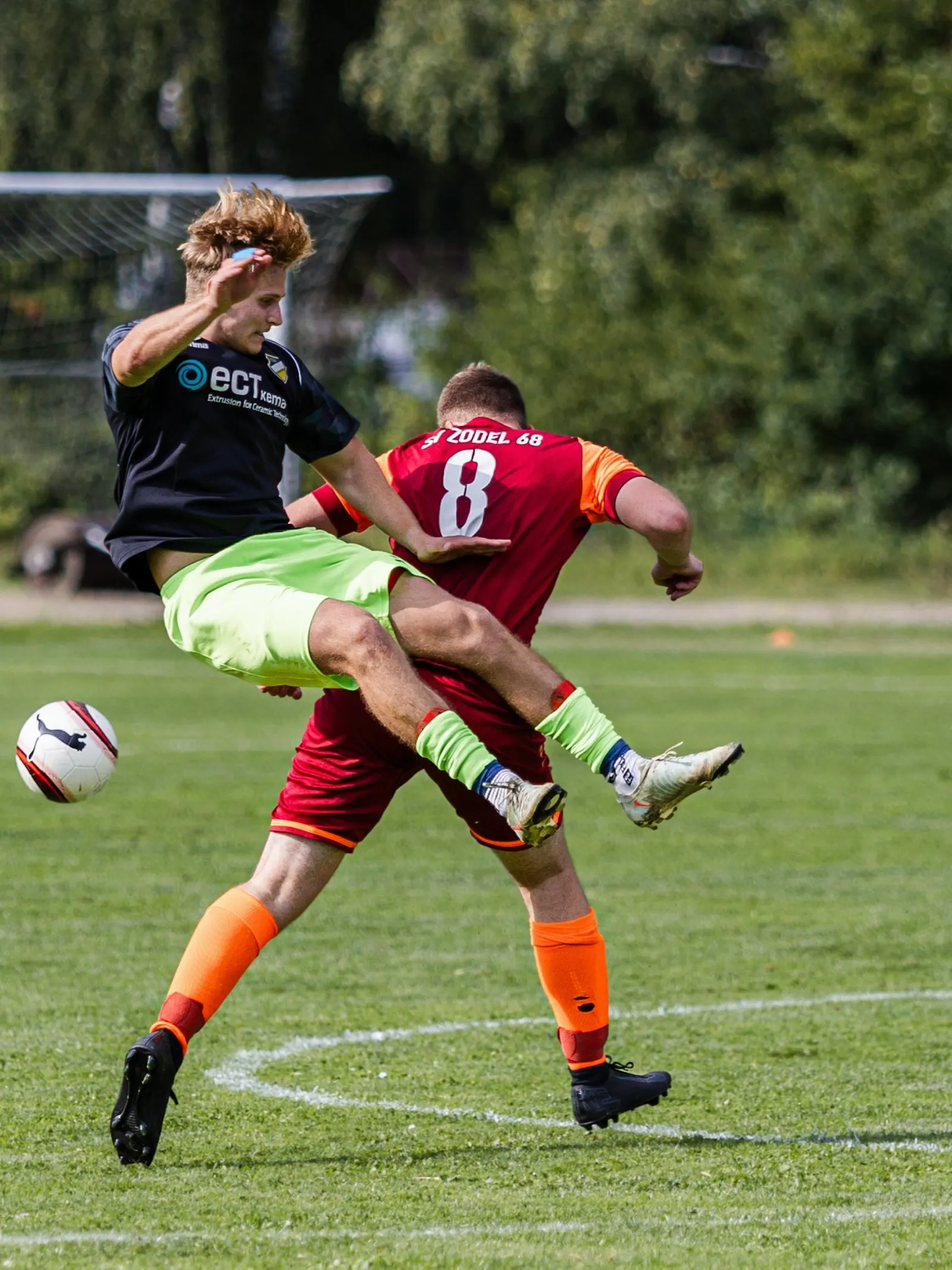 Zweikampf: Ein Spieler springt über das Bein seines Gegenspielers.