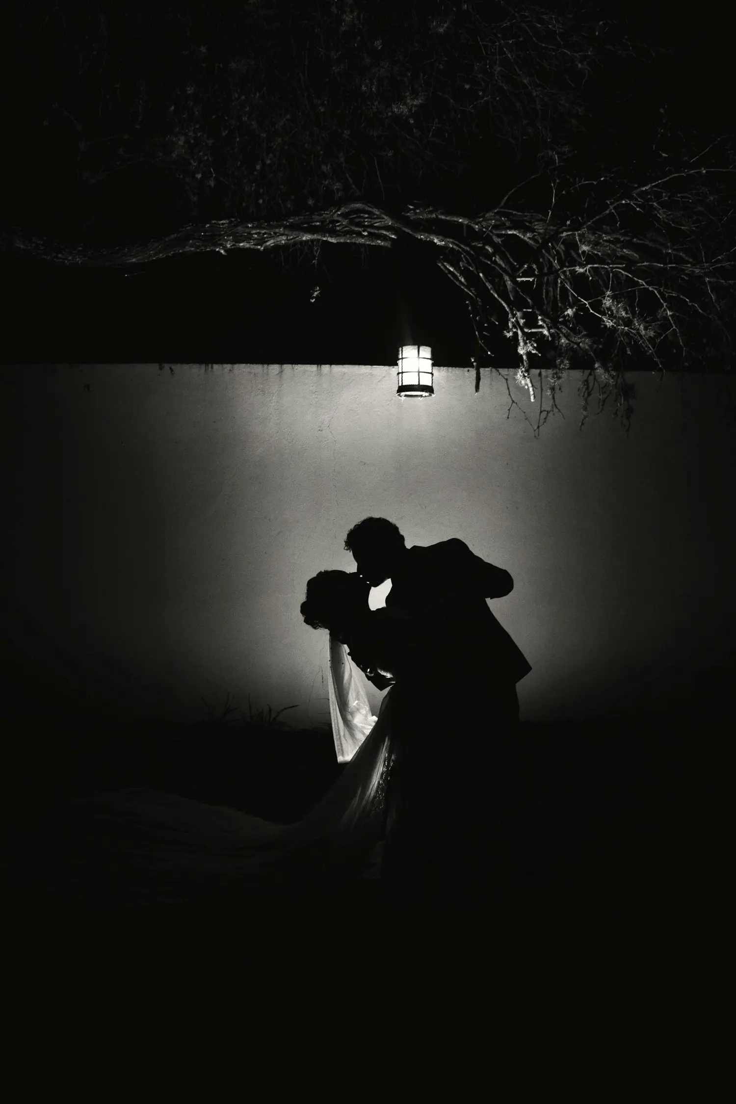 Silhouette eines Brautpaars vor einer angestrahlten Wand.